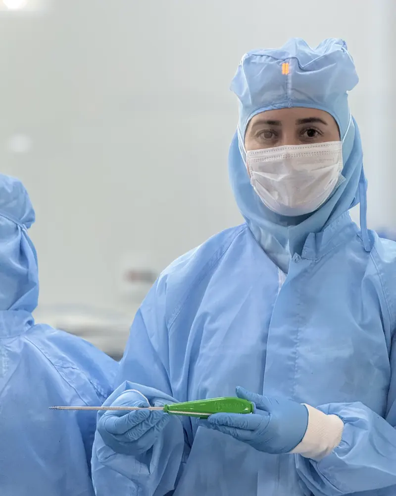 Colaboradora da Sartori com roupa de sala limpa segurando um instrumental